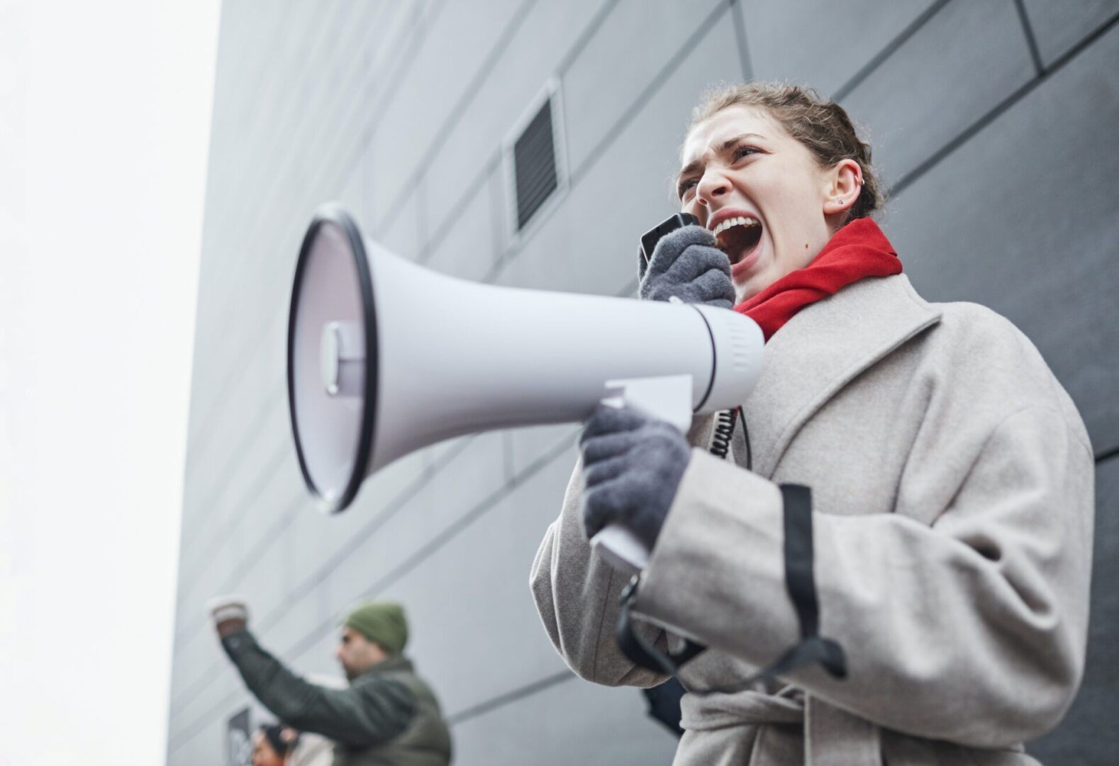 A woman is holding a megaphone and screaming.