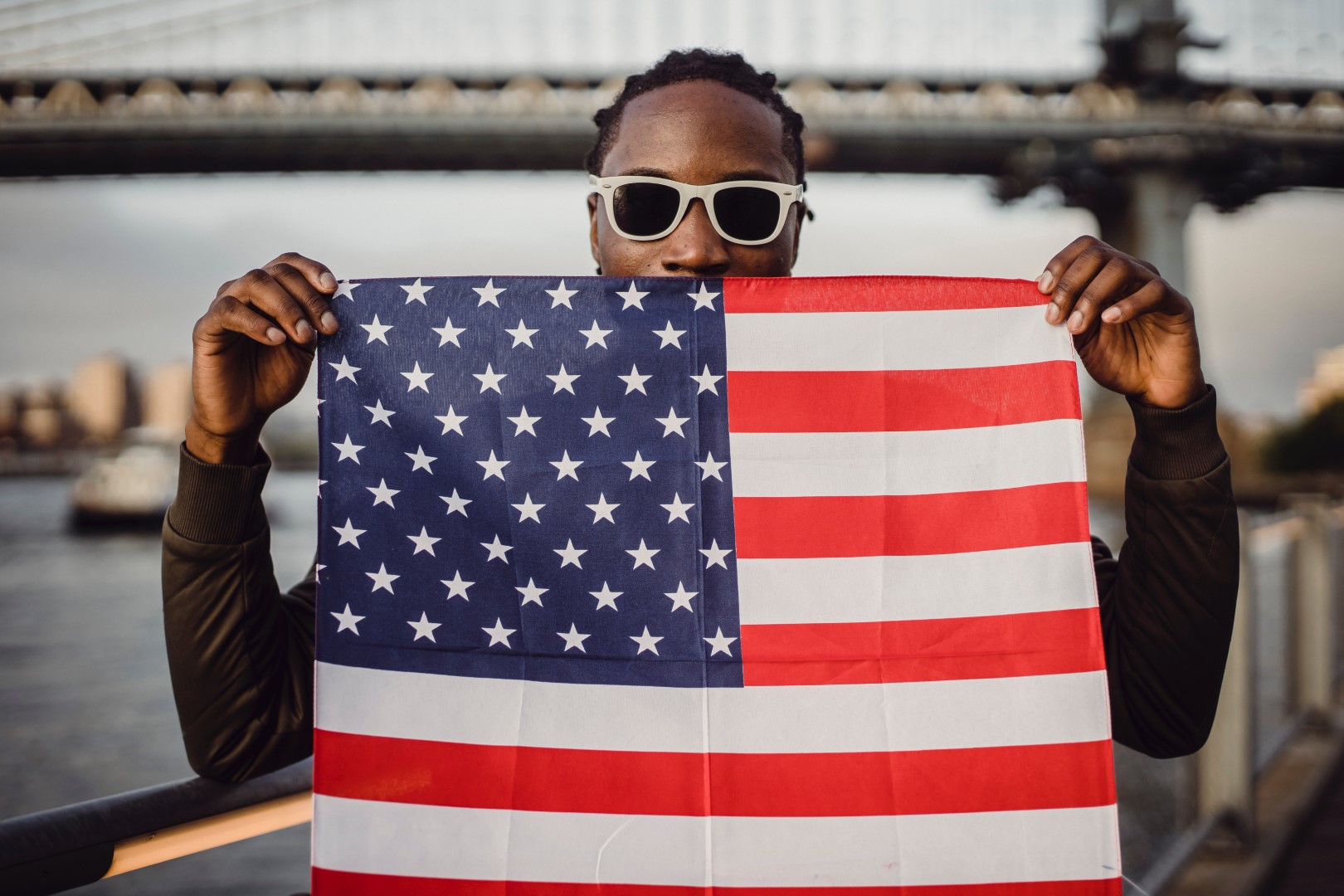 A person holding an american flag in front of their face.